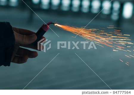Burning Firecracker with Sparks. Guy Holding a Petard in a Hand 84777564