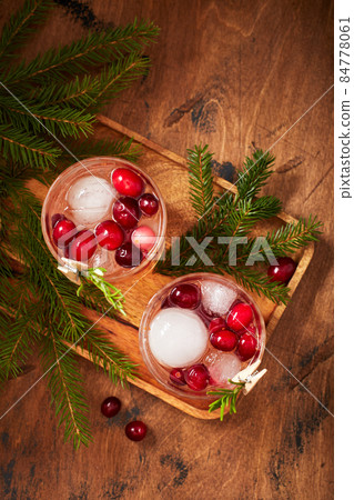 Alcoholic cocktail or non-alcoholic cocktail with vodka and cranberries with ice with fir branches on wooden background Alcoholic cocktail or non-alcoholic cocktail with vodka and cranberries with ice with fir branches on wooden background 84778061