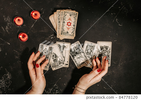 Tarot cards and female hands of fortune teller on black magic table 84778120