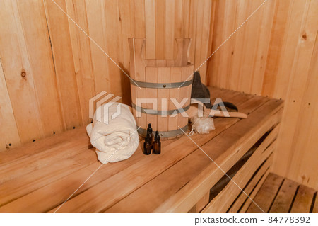 Traditional old Russian bathhouse SPA Concept. Interior details Finnish sauna steam room with traditional sauna accessories set basin towel aroma oil scoop felt. Relax country village bath concept Traditional old Russian bathhouse SPA Concept. Interior details Finnish sauna steam room with traditional sauna accessories set basin towel aroma oil scoop felt. Relax country village bath concept 84778392