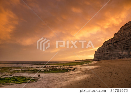Flanked by tall cliffs, the lovely Beach is like a long tongue of golden sand. At low tide the rocks at the end of the beach are exposed. In Lagos,Western Algarve coastline, Portugal. Flanked by tall cliffs, the lovely Beach is like a long tongue of golden sand. At low tide the rocks at the end of the beach are exposed. In Lagos,Western Algarve coastline, Portugal. 84781973