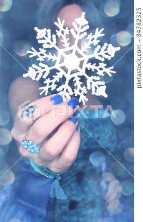 Woman wearing blue dress with snowflake ornament and blue bokeh 84782325