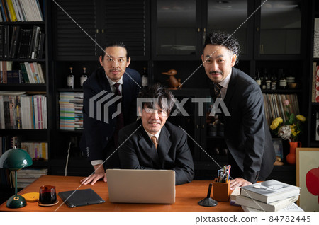 亞洲商人在一個團隊中工作，他們一邊看著電腦一邊思考，一邊看著相機 84782445