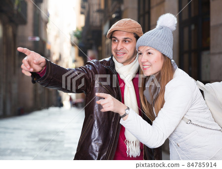 tourists in hats and scarfs pointing finger 84785914