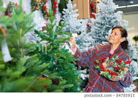 Woman chooses christmas tree at shop 84785915