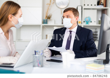 Entrepreneur in medical mask working with female coworker in office 84786248