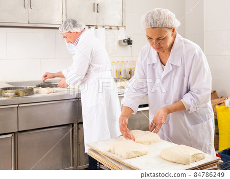 Female baker forming bread loaves from dough 84786249