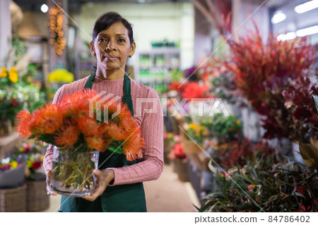 Woman florist in apron arranging bouquet Woman florist in apron arranging bouquet 84786402