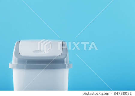 A white trash can with a lid on a blue background. A white trash can with a lid on a blue background. 84788051