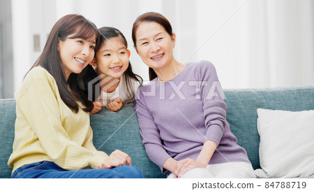 A three-generation family sitting side by side on the sofa 84788719