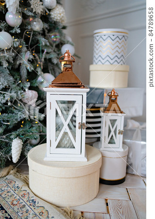 Beautiful white lanterns candlesticks on gift boxes under Christmas tree. Beautiful white lanterns candlesticks on gift boxes under Christmas tree. 84789658