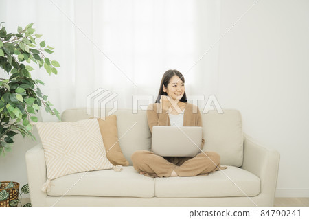 一個女人在家裡使用筆記本電腦(沙發膽量姿勢) 一個女人在家裡使用筆記本電腦(沙發膽量姿勢) 84790241