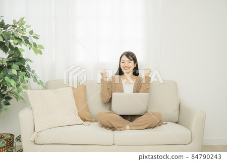 一個女人在家裡使用筆記本電腦（沙發膽量姿勢） 84790243