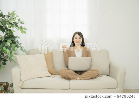 一個女人在家裡使用筆記本電腦(沙發膽量姿勢) 一個女人在家裡使用筆記本電腦(沙發膽量姿勢) 84790245
