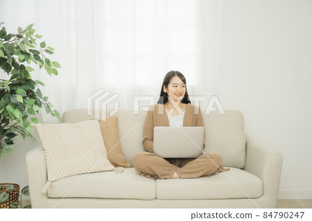 一個女人在家裡使用筆記本電腦(沙發) 一個女人在家裡使用筆記本電腦(沙發) 84790247