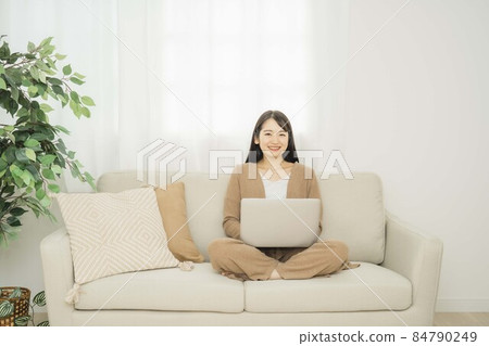 一個女人在家裡使用筆記本電腦(沙發) 一個女人在家裡使用筆記本電腦(沙發) 84790249