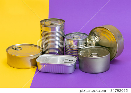 A Group of Stacked Tin Cans with Blank Edges on Split Yellow and Violet Background 84792055