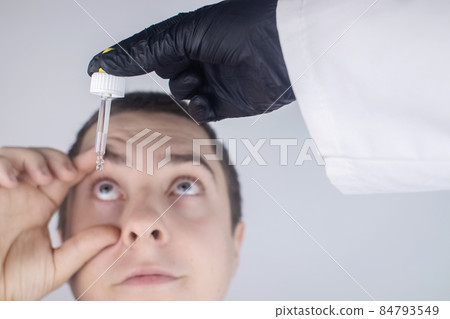 Close-up of eye drops. A man at the doctor appointment, who drips drops into the patient eyes. Concept treatment conjunctivitis, eye fatigue, glaucoma. Viral or bacterial infections Close-up of eye drops. A man at the doctor appointment, who drips drops into the patient eyes. Concept treatment conjunctivitis, eye fatigue, glaucoma. Viral or bacterial infections 84793549
