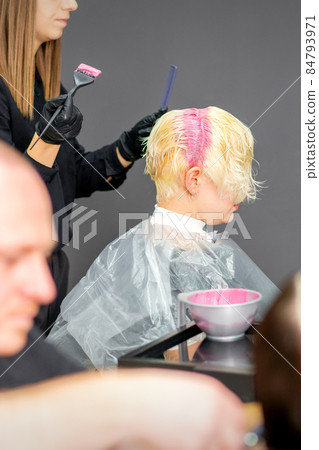 Coloring female hair in the hair salon. Young woman having her hair dyed by beautician at the beauty parlor. Coloring female hair in the hair salon. Young woman having her hair dyed by beautician at the beauty parlor. 84793971