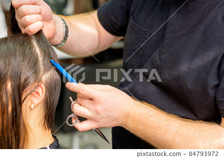 Hairdresser divides female hair into sections with comb holding hair with her hands in hair salon close up. Hairdresser divides female hair into sections with comb holding hair with her hands in hair salon close up. 84793972