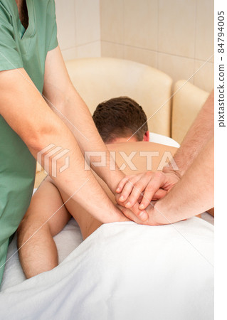 Young man receiving back massage in four hands in spa beauty salon. Young man receiving back massage in four hands in spa beauty salon. 84794005