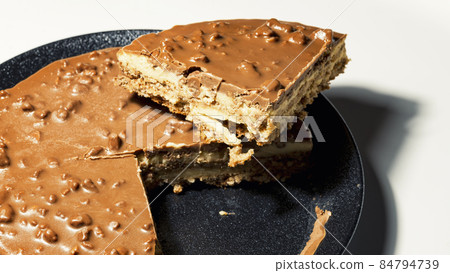 Swedish almond and chocolate cake with a slice cut off, with filling and nuts 84794739
