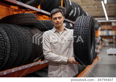 male customer taking new tires in the supermarket. male customer taking new tires in the supermarket. 84794807