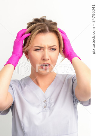 The emotionally shocked young female medical worker holding hands on her head fell into panic on white background, infection, epidemic, virus, and disease concept. The emotionally shocked young female medical worker holding hands on her head fell into panic on white background, infection, epidemic, virus, and disease concept. 84796341