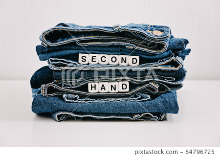 Second hand, Vintage Shopping, slow fashion, Sustainable fashion concept. Stack of blue old denim jeans with the words second hand 84796725
