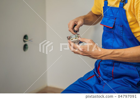 Master electrician installs a socket in the house Master electrician installs a socket in the house 84797091