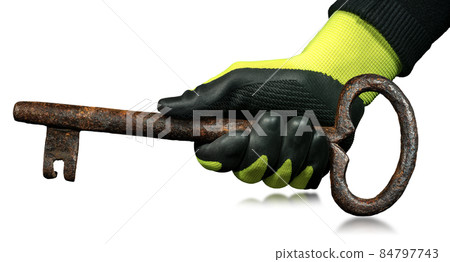 Hand with Protective Work Gloves Holding a Large Rusty Ancient Key 84797743