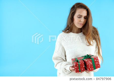 Attractive woman holds gift boxes on blue background Attractive woman holds gift boxes on blue background 84797906
