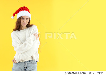 Attractive woman in Santa hat on yellow background Attractive woman in Santa hat on yellow background 84797994