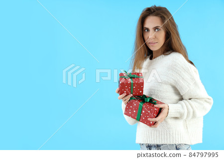 Attractive woman holds gift boxes on blue background Attractive woman holds gift boxes on blue background 84797995