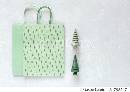 Green paper Christmas bags and wooden Christmas trees on grey background Green paper Christmas bags and wooden Christmas trees on grey background 84798347