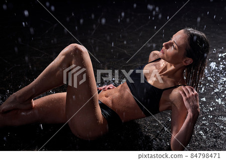 attractive leggy athletic fitness woman model, wearing black underwear lays on floor 84798471