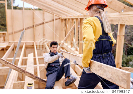 Two Specialists Measuring Examining The Size Of Wooden Beam During Cottage Building Two Specialists Measuring Examining The Size Of Wooden Beam During Cottage Building 84799347