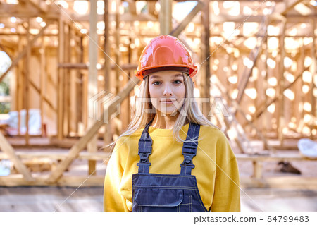 lady in hardhat posing against New residential construction home framing 84799483
