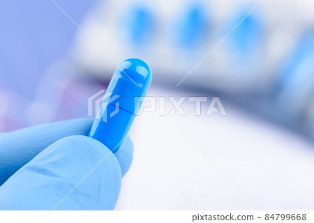 Scientist hold in hand blue pill capsule.  84799668
