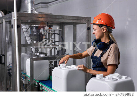 female in hardhat closes the lid of canister container with pesticides, preparing 84799998