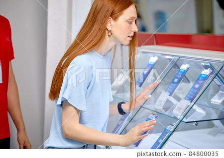 Female Interested In Smartphone In Store, Make Purchase, In Casual Wear 84800035