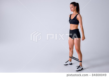 caucasian sports fitness woman in sportswear working out with elastic band isolated 84800049