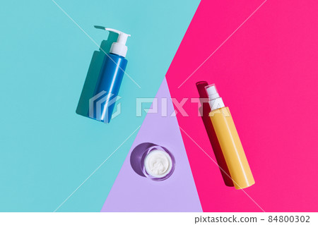 Top view ot set of different cosmetic jars, bottles and pot for cream without logos isolated over colored background. 84800302