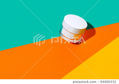 Closed glass cream pot with copy space for your brand isolated on bright colored background. Mockup 84800332