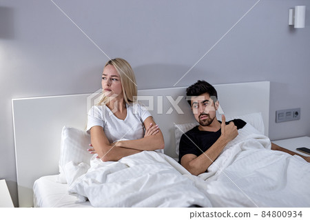 Unhappy young woman and man not talking after quarrel, on bed at home 84800934