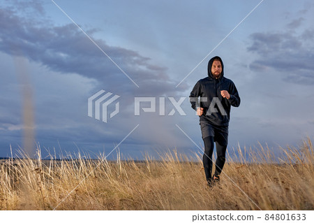 man jogging in field wearing black sportswear, practice running on fresh air man jogging in field wearing black sportswear, practice running on fresh air 84801633