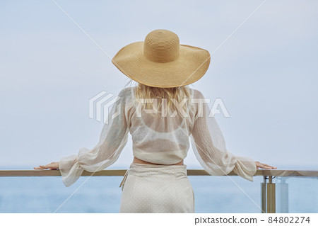 Back view of the Woman in Elegant Beach Outfit Outdoors Against Sea Background During Summer Vacations 84802274