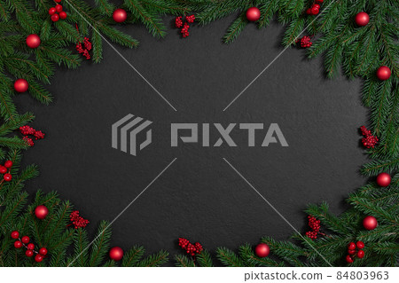 Christmas frame with fir branches and red berries, baubles on a black background. Xmas greeting card. Happy New Year. Copy space, top view, flat lay. Christmas frame with fir branches and red berries, baubles on a black background. Xmas greeting card. Happy New Year. Copy space, top view, flat lay. 84803963