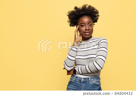 Half-length portrait of young African woman in warm casual style clothes isolated on yellow background. Concept of emotions Half-length portrait of young African woman in warm casual style clothes isolated on yellow background. Concept of emotions 84804432