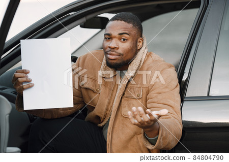Black man with a confused face impression holding sheet of paper Black man with a confused face impression holding sheet of paper 84804790